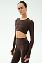 A woman stands against a plain light background in a matching dark brown long-sleeve crop top and high-waisted leggings, her yoga-ready look finished with the SPLITS59 Amelia Airweight Lite Shrug in Dark Chocolate.