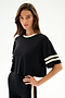 Woman wearing the SPLITS59 Djuna Oversized Crop Jersey Tee - Black/Creme, a relaxed crop top, standing against a plain light background.