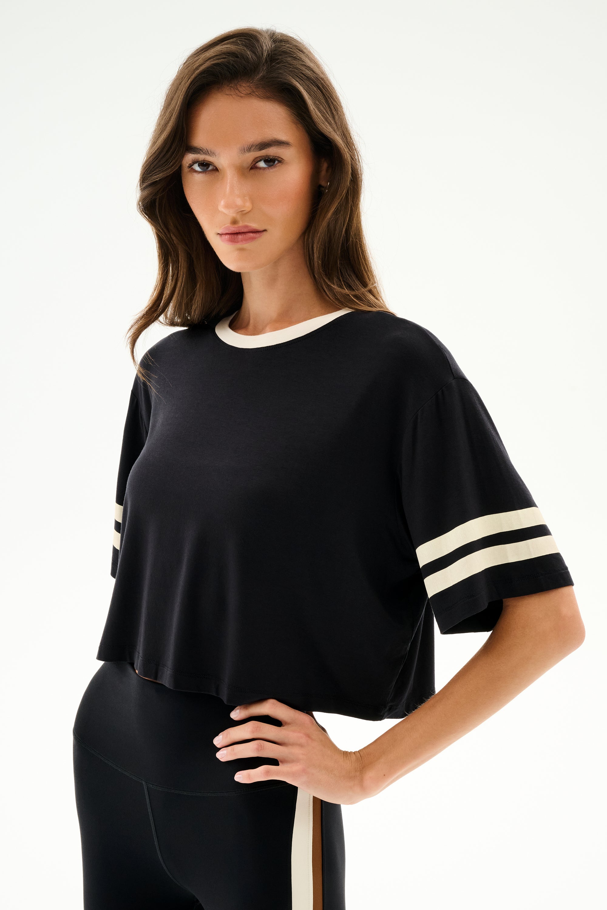 Woman wearing the SPLITS59 Djuna Oversized Crop Jersey Tee - Black/Creme, a relaxed crop top, standing against a plain light background.