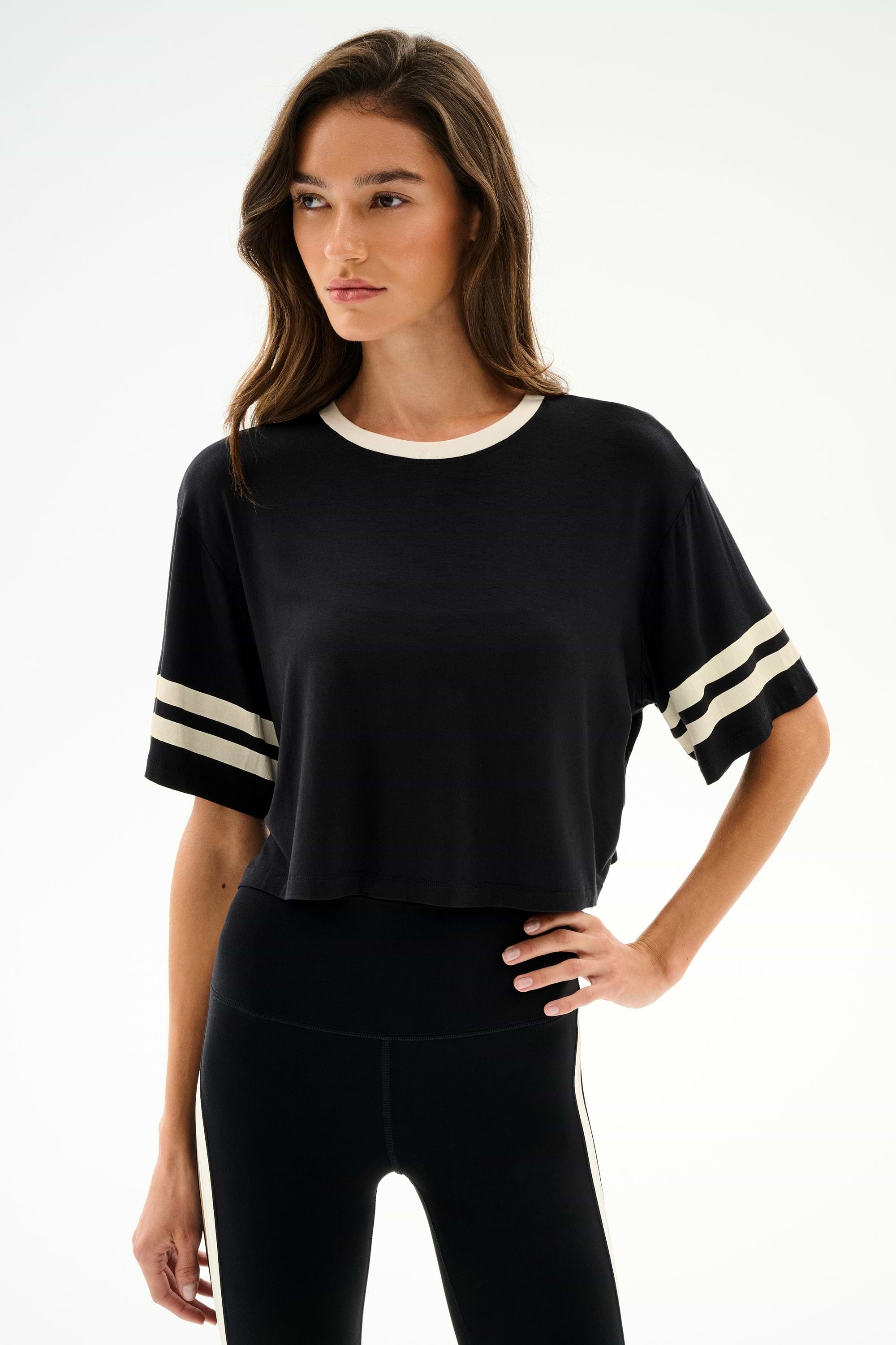 Model wears the SPLITS59 Djuna Oversized Crop Jersey Tee - Black/Creme with matching black leggings, standing against a plain white background.