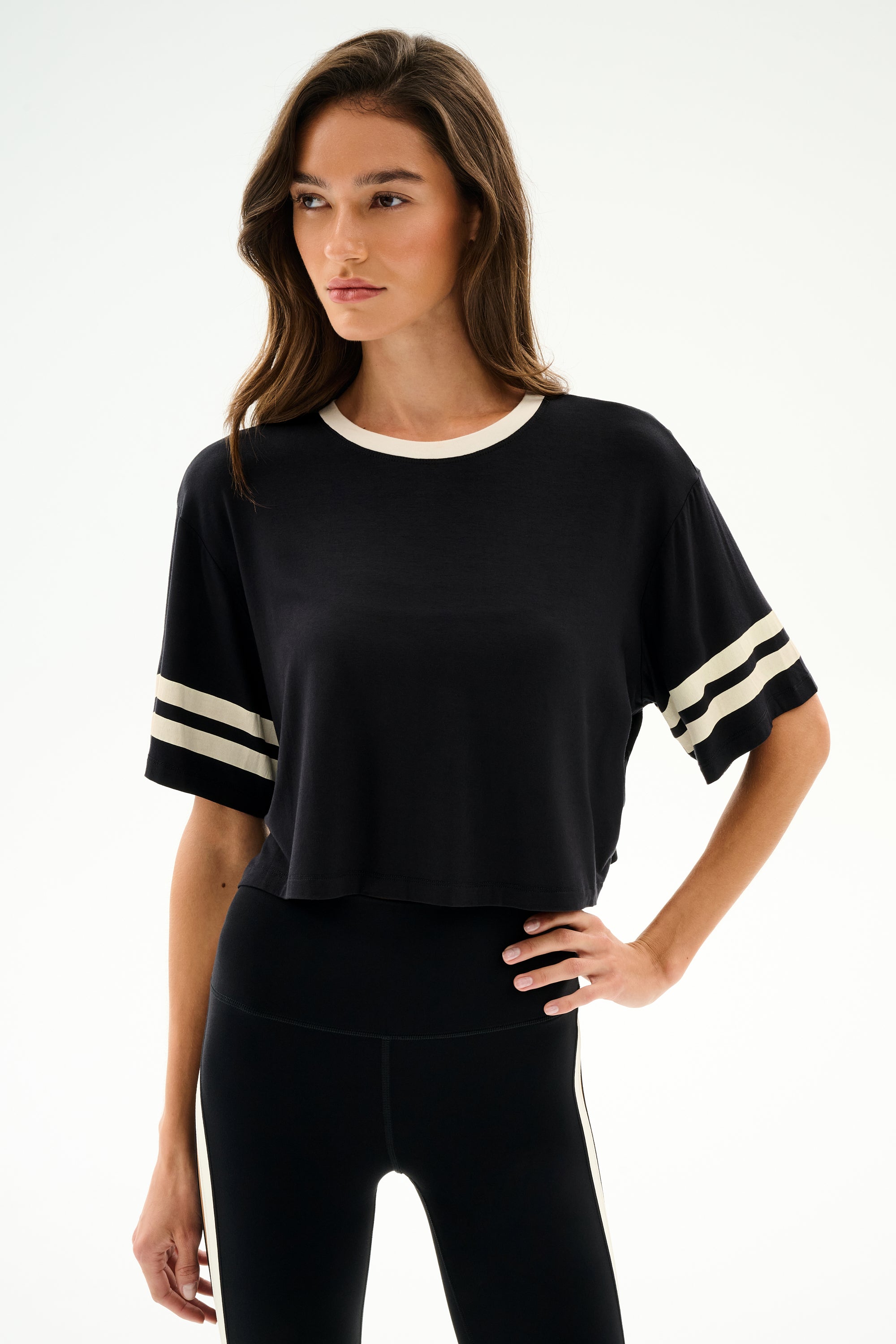 Model wears the SPLITS59 Djuna Oversized Crop Jersey Tee - Black/Creme with matching black leggings, standing against a plain white background.