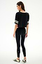 A woman poses on a white background, wearing the SPLITS59 Djuna Oversized Crop Jersey Tee - Black/Creme, paired with leggings and striped sneakers.