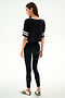 A woman poses on a white background, wearing the SPLITS59 Djuna Oversized Crop Jersey Tee - Black/Creme, paired with leggings and striped sneakers.