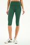 A person wearing SPLITS59 Ella High Waist Airweight Capri in Arugula/White, paired with white Adidas sneakers, stands against a plain background.
