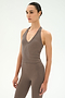 A person wearing the SPLITS59 June Rib Halter in Lentil, a taupe ribbed sleeveless V-neck top, paired with matching high-waisted leggings made from stretchy material, standing against a plain light background.