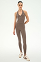 A woman stands facing forward against a plain white background wearing the SPLITS59 June Rib Halter in Lentil—a taupe halter-neck tank top crafted from modal fabric—paired with matching high-waisted leggings made from stretchy material and off-white sneakers with maroon stripes.