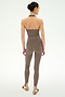A woman stands against a white background, facing away, wearing the SPLITS59 June Rib Halter in Lentil paired with matching leggings, both crafted from stretchy material, and flat sandals.