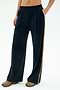 A person wears the SPLITS59 Luca Airweight Trouser with Stripe in Indigo/Honey, styled with colorful sneakers and a bare midriff, standing with one hand in their pocket against a plain background.