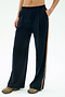 A person wears the SPLITS59 Luca Airweight Trouser with Stripe in Indigo/Honey, styled with colorful sneakers and a bare midriff, standing with one hand in their pocket against a plain background.