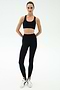 A person stands facing forward, wearing SPLITS59 River High Waist Airweight Stirrup leggings in black and a black sports bra, paired with white sneakers against a plain light background.