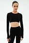 A woman stands against a plain white background wearing the SPLITS59 Amelia Airweight Lite Shrug in black with matching high-waisted leggings.