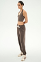 A person stands in profile against a plain white background, wearing the SPLITS59 Andie Oversized Fleece Sweatpant in Lentil—a brown drawstring sweatpant with added spandex for stretch—paired with a matching brown modal halter crop top and white sneakers featuring brown stripes.
