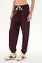 Wearing the SPLITS59 Andie Oversized Fleece Sweatpant in Dark Cherry, featuring a white drawstring, this outfit is paired with cream sneakers accented by brown stripes. The ultra-luxe fleece joggers, crafted in Los Angeles, are ideal for cool weather workouts and are shown against a plain white background.