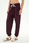 Wearing the SPLITS59 Andie Oversized Fleece Sweatpant in Dark Cherry, featuring a white drawstring, this outfit is paired with cream sneakers accented by brown stripes. The ultra-luxe fleece joggers, crafted in Los Angeles, are ideal for cool weather workouts and are shown against a plain white background.