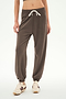 A person wearing the SPLITS59 Andie Oversized Fleece Sweatpant in Lentil, paired with beige sneakers featuring dark stripes, stands against a plain background.
