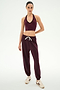 A woman stands against a plain background, wearing a burgundy halter crop top, the SPLITS59 Andie Oversized Fleece Sweatpant in Dark Cherry—ultra luxe and made in Los Angeles—and white sneakers with burgundy accents, perfect for cool weather workouts.