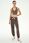 A woman stands facing forward against a plain white background, wearing SPLITS59 Andie Oversized Fleece Sweatpant in Lentil with a brown halter crop top and white sneakers.