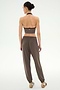 A woman stands facing away against a plain light background, wearing the SPLITS59 Andie Oversized Fleece Sweatpant in Lentil, styled with a strapless dark crop top and beige sandals.