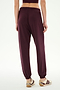 Model is shown from the back wearing SPLITS59 Andie Oversized Fleece Sweatpant in Dark Cherry with sneakers, standing against a plain white background—ideal for cool weather workouts.