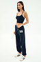 A woman wears the SPLITS59 Andie Oversized Fleece Varsity 59 Sweatpant in Indigo/59, paired with a navy crop top and white sneakers with navy stripes, standing against a plain white background. Made in Los Angeles.
