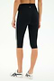 Model wears SPLITS59 Ella High Waist Airweight Capri in Black/White, featuring white side stripes, paired with white sneakers. Shown from the back against a plain background—sleek style and comfort for any workout.