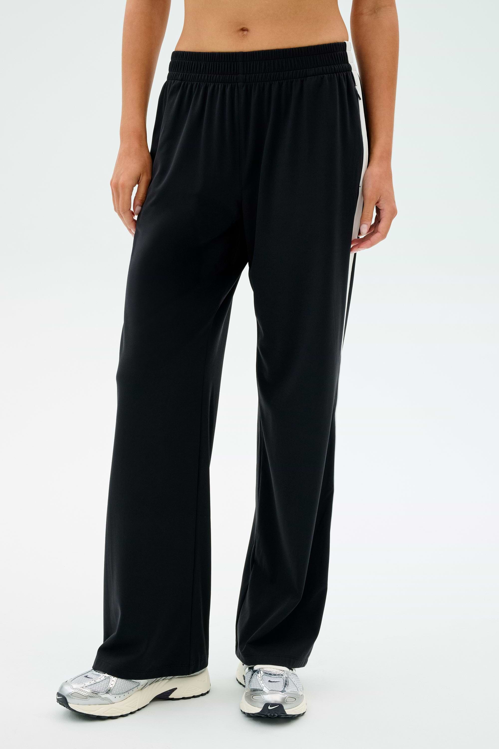 Individual wearing SPLITS59 Maxie Rigor Track Pant in Black/White paired with white sneakers against a plain background.