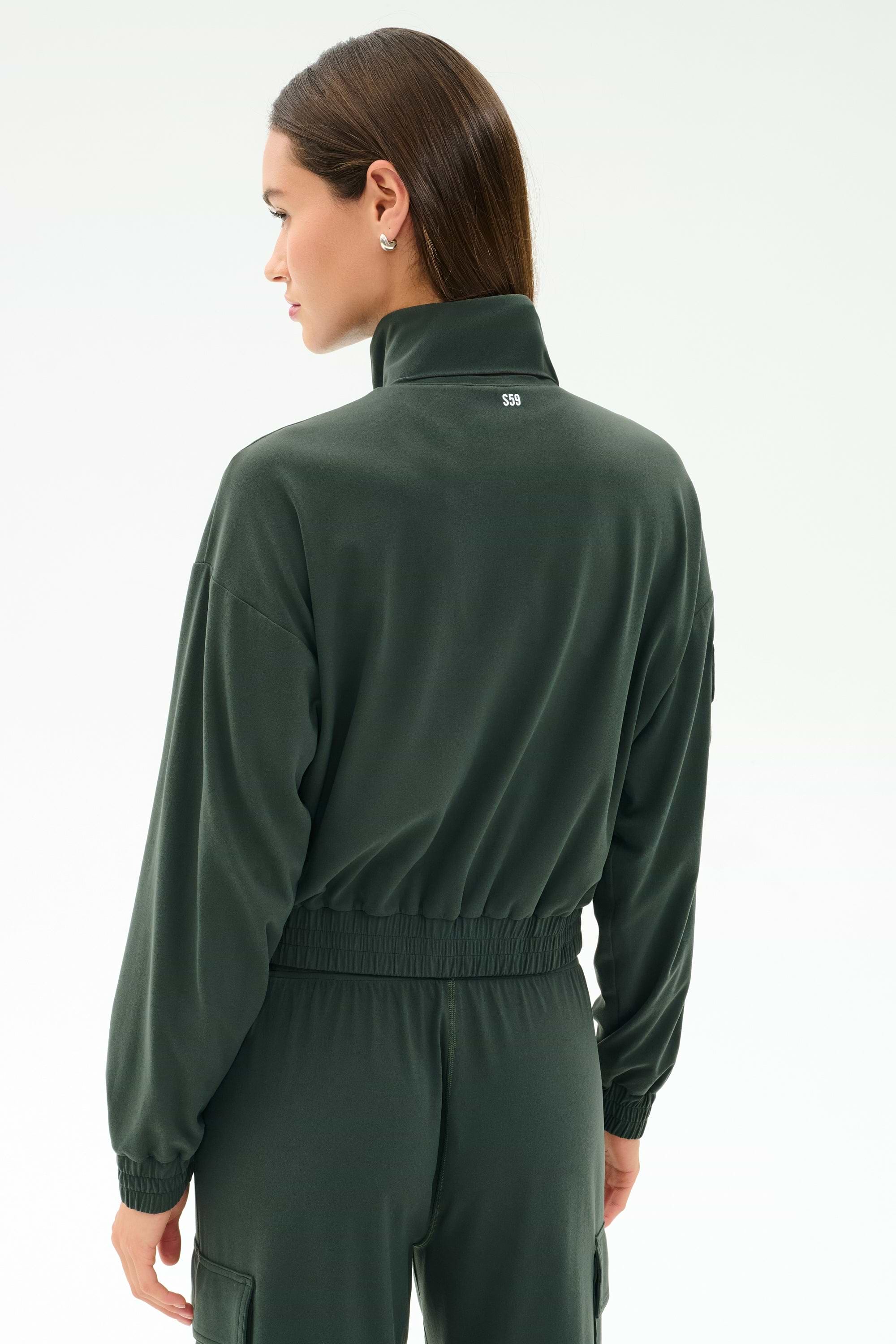 A person seen from behind, head turned left, wears the Peaches Airweight Cargo Jacket - Military by SPLITS59.