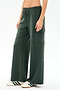 A person wears SPLITS59’s Alex Airweight Cargo Pant in Military, featuring a soft nylon blend, paired with white sneakers with green stripes, standing against a plain light background.
