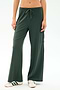 A person wearing SPLITS59 Alex Airweight Cargo Pant - Military, dark green wide-leg spandex blend pants with a side pocket, paired with white sneakers featuring green stripes, shown from waist to feet.