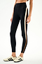 A woman wearing SPLITS59 Emerson Airweight High Waist 7/8 - Black/Creme leggings and cream sneakers with black stripes, standing against a plain white background.