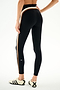 A person wears SPLITS59 Emerson Airweight High Waist 7/8 - Black/Creme leggings with white sneakers, standing against a plain white background.