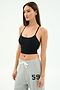 A woman wears the SPLITS59 Airweight Crop - Black and light gray sweatpants with "59" on the left, standing against a white background—an ideal look for hot yoga or stylish lounging.