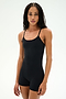 A person with long braided hair wears the SPLITS59 Airweight 3.5" Short Jumpsuit in black, standing against a plain light background and looking at the camera with a neutral expression.