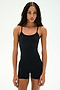 A woman stands facing forward in the SPLITS59 Airweight 3.5" Short Jumpsuit in black, featuring spaghetti straps and crafted from soft Airweight fabric, against a plain white background.