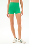 A person wears SPLITS59’s Airweight High Waist 3.5” Short in Spearmint and white sneakers with green stripes, standing against a plain white background.