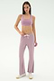 A woman stands against a white background wearing SPLITS59's Blaire Rib Pant in Blush, a coordinating mauve spandex sports bra, and white sneakers.