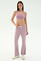 A woman stands against a white background wearing SPLITS59's Blaire Rib Pant in Blush, a coordinating mauve spandex sports bra, and white sneakers.