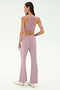 A woman faces away, wearing the SPLITS59 Blaire Rib Pant in blush with a matching lavender sports bra and white sneakers, set against a plain, light background. The outfit is crafted from soft modal fabric with added spandex for comfort.
