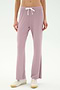 A person wears SPLITS59's Blaire Rib Pant in Blush, crafted from soft modal fabric, paired with white sneakers. Only the lower torso and legs are shown, standing against a plain light background.