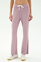 A person wears SPLITS59's Blaire Rib Pant in Blush, crafted from soft modal fabric, paired with white sneakers. Only the lower torso and legs are shown, standing against a plain light background.
