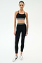 A person wearing the SPLITS59 Cali Active Rib Bra in black and high-waisted black leggings with white stripes, paired with white sneakers, stands against a plain white background.