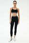 A person wearing the SPLITS59 Cali Active Rib Bra in black and high-waisted black leggings with white stripes, paired with white sneakers, stands against a plain white background.