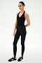 A person stands against a plain white background wearing the SPLITS59 June Rib Halter in black, black leggings with stirrups crafted from a soft modal blend with spandex for added stretch, and black athletic shoes.