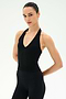 Model with hair slicked back poses in the SPLITS59 June Rib Halter - Black, a sleeveless V-neck top made from a soft modal blend with spandex for comfortable stretch, paired with matching black leggings, against a plain white background.