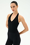 Model with hair slicked back poses in the SPLITS59 June Rib Halter - Black, a sleeveless V-neck top made from a soft modal blend with spandex for comfortable stretch, paired with matching black leggings, against a plain white background.
