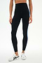 A person wearing SPLITS59 Ella High Waist Airweight 7/8 leggings in Black/Classic Blue, paired with white sneakers, standing against a plain white background.
