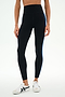 A person wearing SPLITS59 Ella High Waist Airweight 7/8 leggings in Black/Classic Blue, paired with white sneakers, standing against a plain white background.