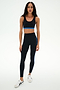 A person is wearing the SPLITS59 Ella High Waist Airweight 7/8 leggings in Black/Classic Blue, paired with a black sports bra and white athletic shoes, standing against a plain white background.