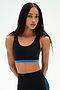 A woman with long braided hair wears the SPLITS59 Maci Airweight Bra in Black/Classic Blue and matching high-waisted nylon spandex leggings, standing against a plain white background.