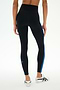 A person wearing SPLITS59 Ella High Waist Airweight 7/8 leggings in Black/Classic Blue and white sneakers stands against a plain light background.
